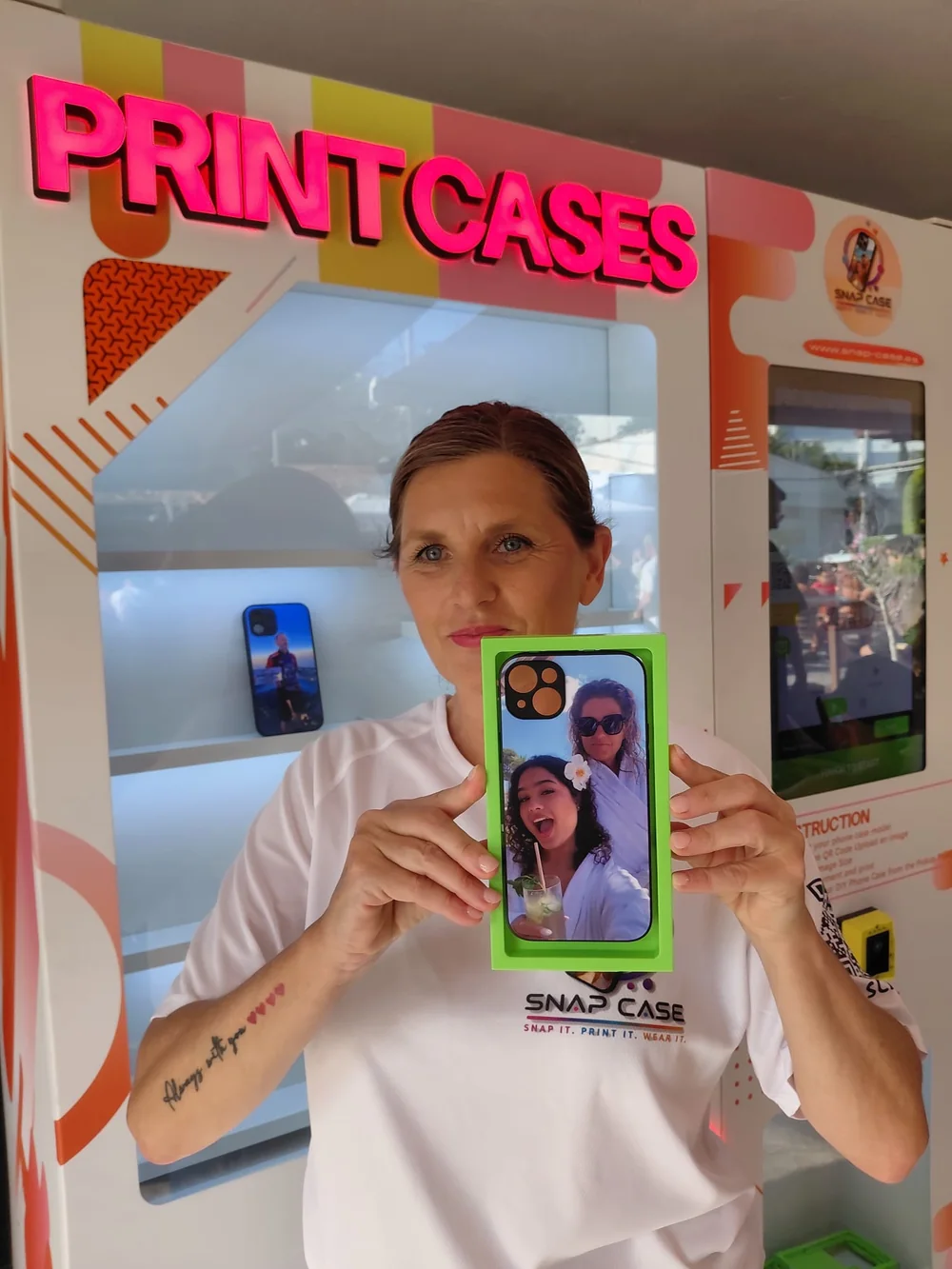 Una clienta sostiene su funda recién impresa delante de la máquina Snap Case